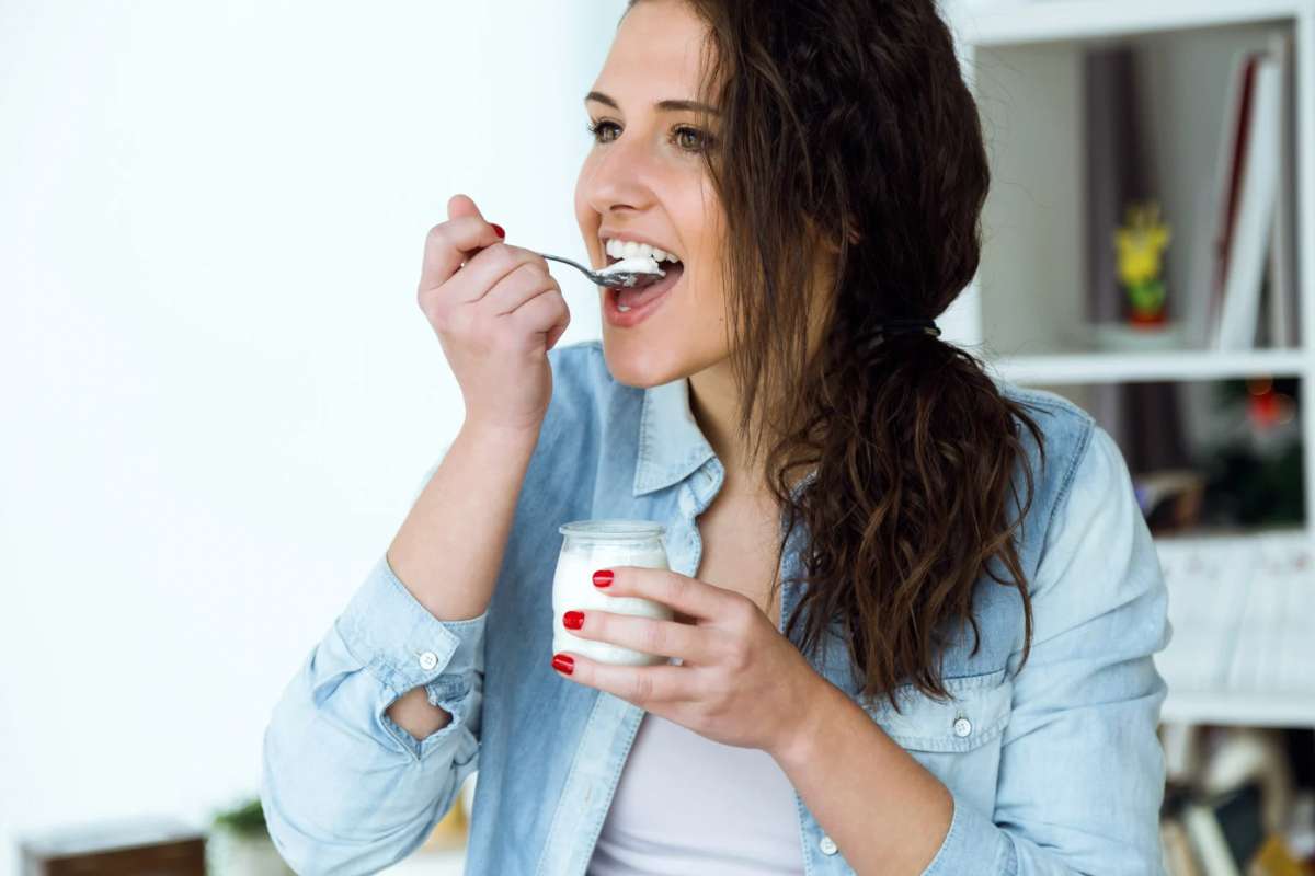 Donna che mangia lo yogurt con il cucchiaino