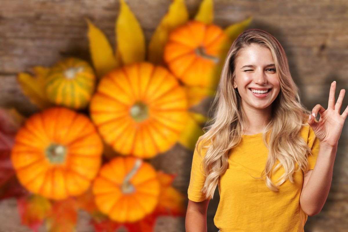 zucca su sfondo di legno e donna sorridente che fa ok con le mani