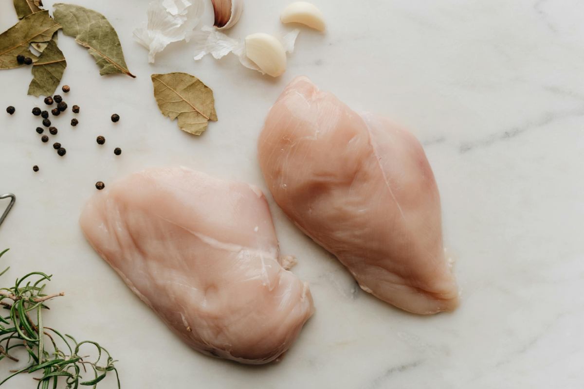 Due fettine di petto di pollo su un piano con aglio e spezie