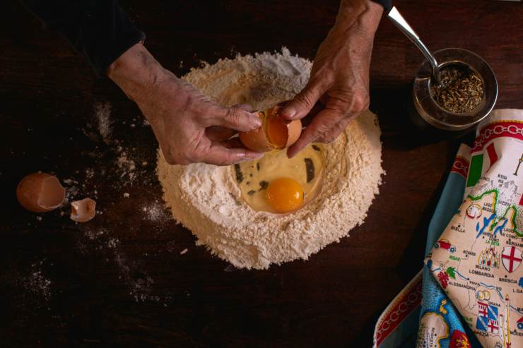 Uomo che mette le uova dentro alla farina