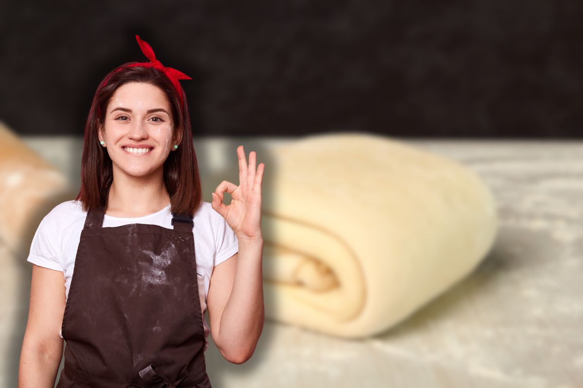 panetto di pasta sfoglia e mattarella su piano da lavoro e donna sporca di farina che fa ok con le mani