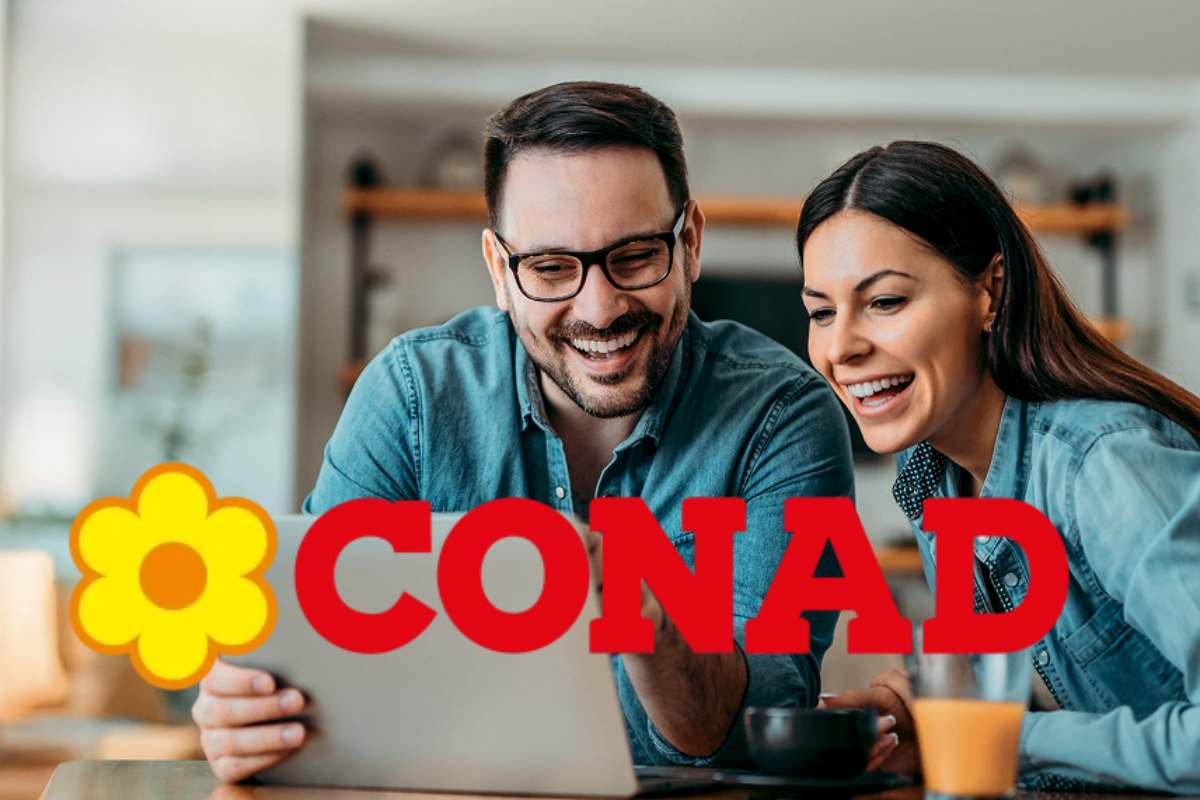 Una coppia sorridente di fronte a laptop e, in evidenza, il logo di Conad