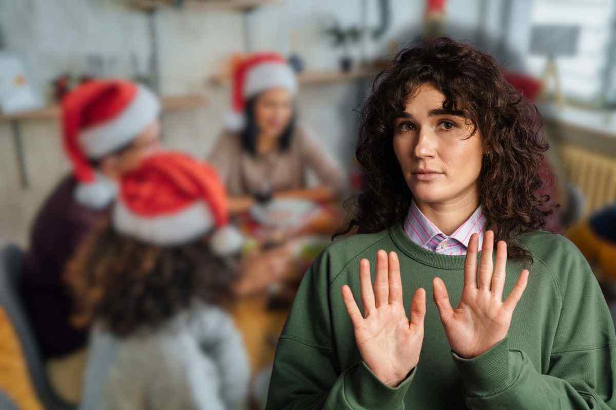 persone sedute a tavola nel giorno di natale e donna che fa stop con le mani 