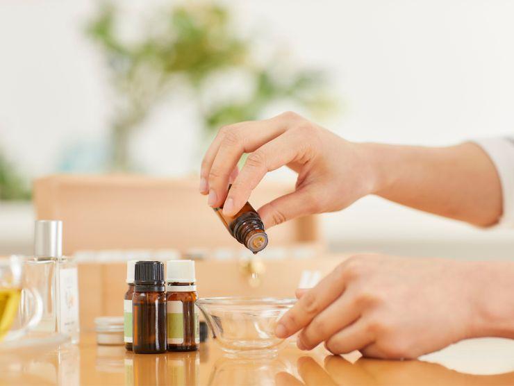 persona che sta versando delle gocce di olio essenziale in una ciotola