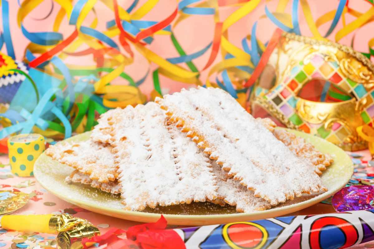 chiacchiere di carnevale in un piatto in mezzo a stelle filanti