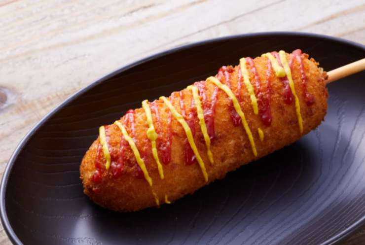 corn dog dorato in piatto nero