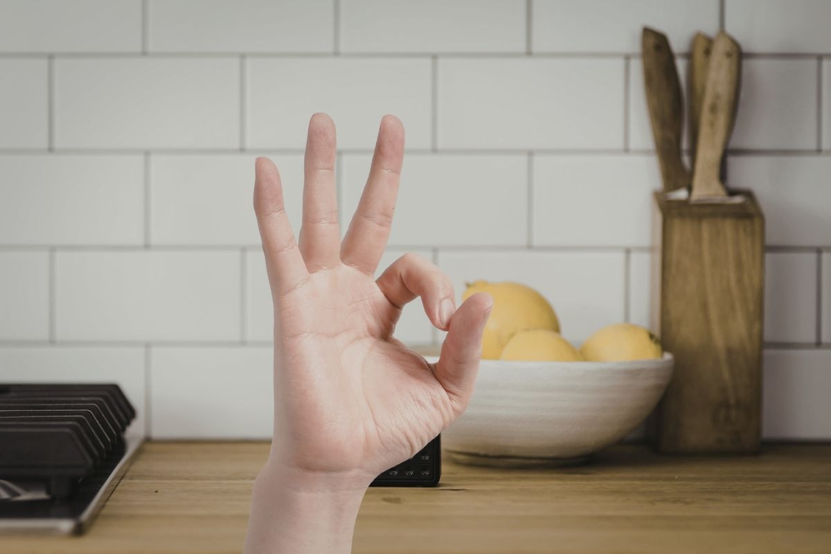 sfondo di una parete della cucina e una mano che fa ok in primo piano